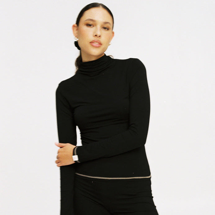 Woman wearing a black turtleneck sweater on a light gray background